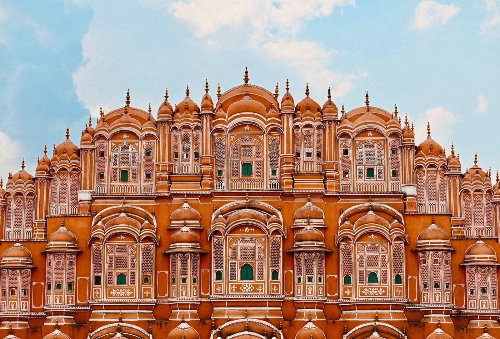 Iconic facade of Hawa Mahal in Jaipur, showcasing intricate Rajput architecture under a clear sky.