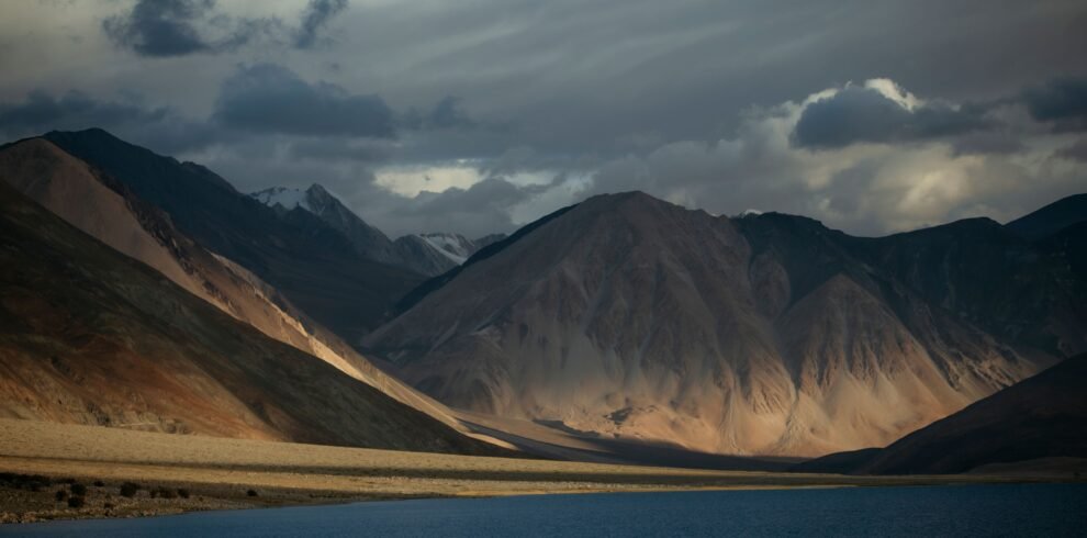 Breathtaking view of Pangong Lake with mountains and dynamic clouds in Ladakh, India.