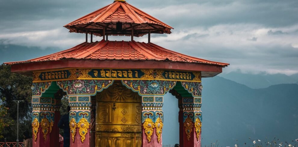 A colorful Buddhist prayer wheel pavilion set against the scenic mountains in Pelling, Sikkim, India.