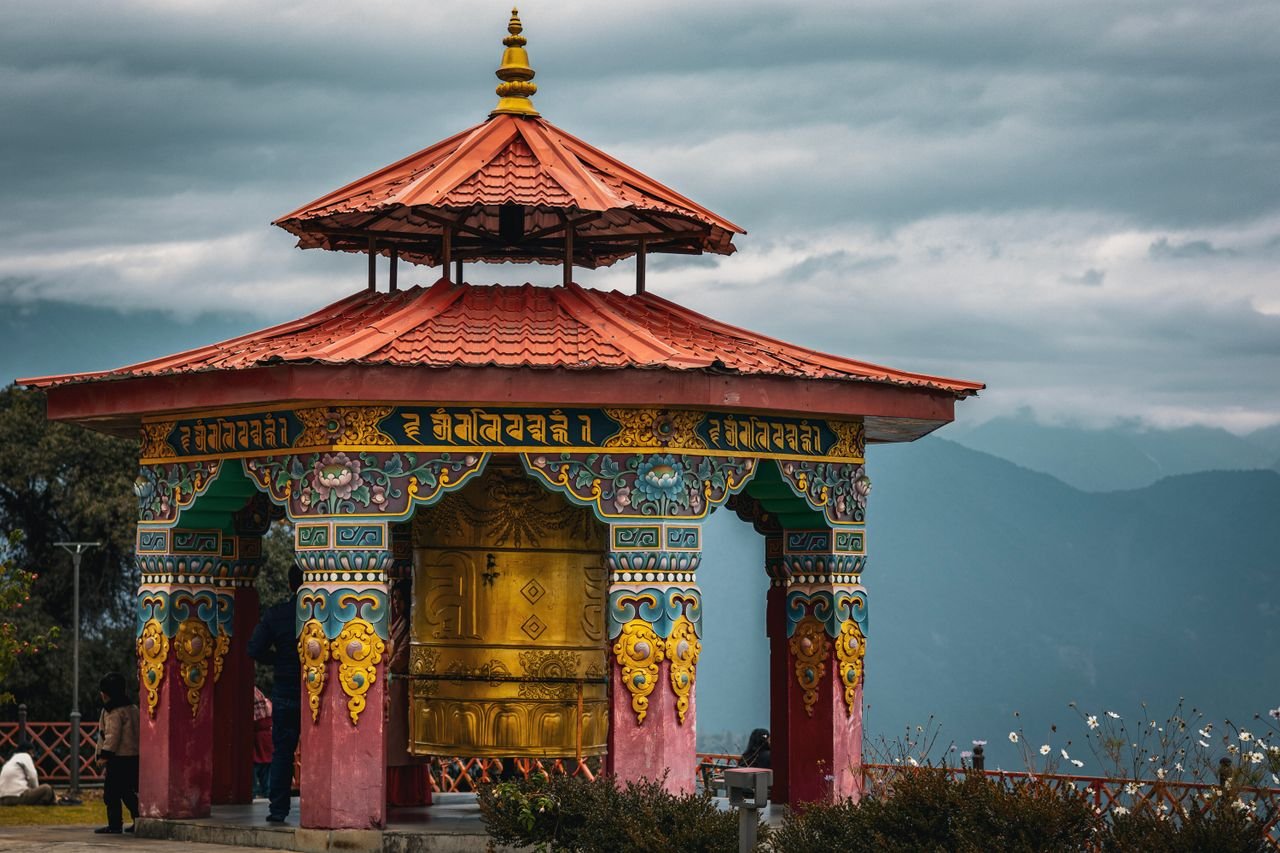 A colorful Buddhist prayer wheel pavilion set against the scenic mountains in Pelling, Sikkim, India.